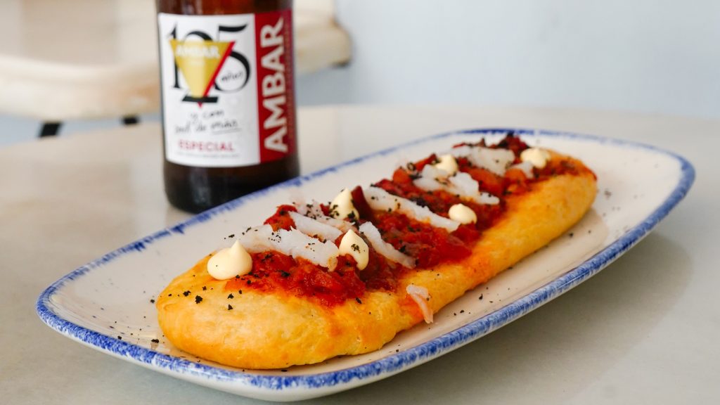 Coca artesanal de la III Ruta de les Coques by Ambar en Alenar Bodega Mediterránea, Valencia, acompañada de cerveza Ambar Especial.