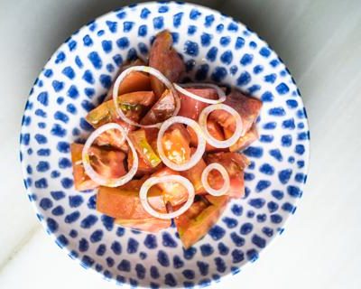 Ensalada de tomate de temporada con cebolleta fresca y aceite de ajo
