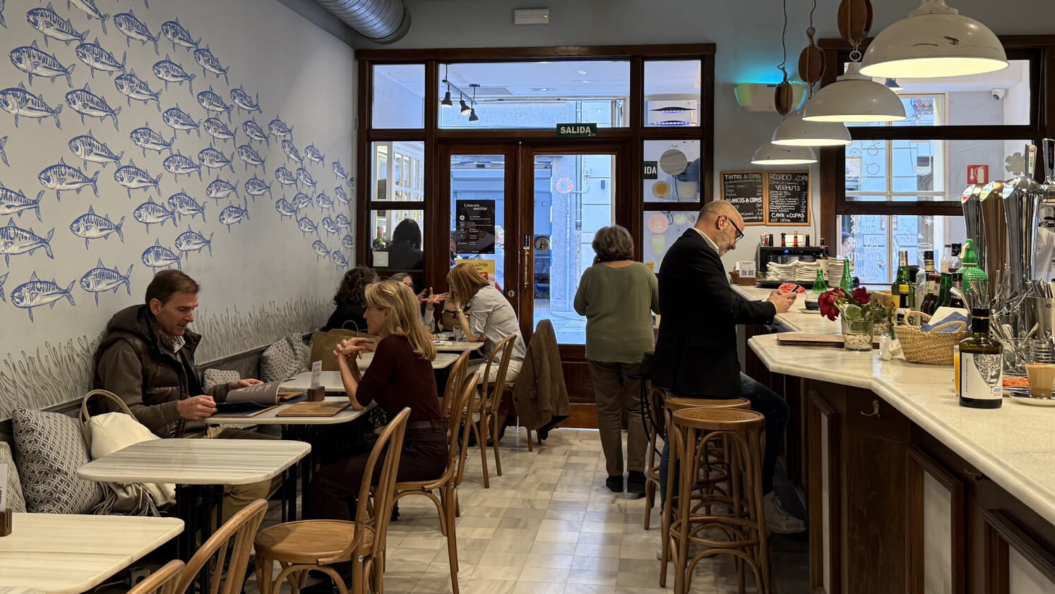 Personas consumiendo dentro de un bar mediterráneo.